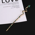 Gothic gold snake hair pin with green enamel and crystal accents on a minimal background - Gold