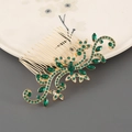 Detail van vintage gouden haarkam met groene strass steentjes op keramisch bord - Goud met groene steen