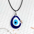 Detalle macro del colgante de ojo turco de cristal azul en forma de gota azul - Estilo Gota de Agua / 3x4cm / Azul Zafiro