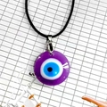 Vista detallada del colgante de ojo de mal de ojo en cristal violeta con cordón negro - Estilo Redondo / 30MM / Púrpura