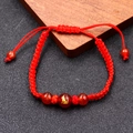 Macro detail of red woven rope bracelet featuring red agate beads and golden zodiac dog - Dog Zodiac (BN-0174)