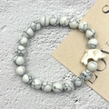 Dettaglio del bracciale elastico in turchese bianco con un ciondolo a forma di delfino - Delfino Howlite Bianca