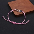 Detailansicht eines rosa geflochtenen Armbands mit drei ineinandergreifenden Herzanhängern - Pink And Silver Triple Heart Bracelet