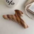Elegant brown marble pattern claw clip for hair styling with glossy finish on a wood tray - Hanger Style