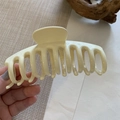 Large cream resin hair claw clip with multiple teeth for thick hair shown in a hand - Off White