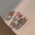 Gros plan de cinq barrettes à cheveux pêche rose avec feuilles vertes et clips métalliques - Style Pêche Rose