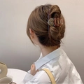 Dettaglio molletta per capelli a forma di cuore ambra marmorizzato su acconciatura raccolta - Marrone
