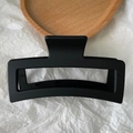 Detailed top view of a large 13cm matte black rectangular hair claw clip on a wooden tray - Black