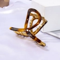 Macro detail of tortoiseshell acetate and golden metal hair claw clip on white silk - Glazed Coffee