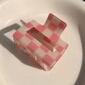 Detailed view of pink and white checkered hair claw clip on a white ceramic plate - Light Pink