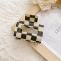 Detail view of square black and white checkerboard hair claw clip on aesthetic background - Black and White