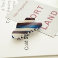 Detail view of large acetic acid hair claw with colorful gradient patterns on a magazine - Gradient Blue