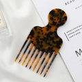Elegant tortoiseshell acetate wide-tooth hair comb on white silk and magazine backdrop - Tortoise