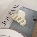 Detail einer cremeweißen, glänzenden Haarklammer auf einem Magazin für tägliches Styling - Gebrochenes Weiß