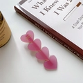 Détail d'une barrette à cheveux rose en forme de cœur en acétate sur bureau blanc - Rose Pêche