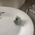 Vue détaillée de la pince à cheveux en forme de chat avec texture marbrée dans un plat blanc - Vert