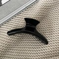 Polished black acetate hair claw clip for thick hair shown on a cozy knit fabric background - 11.5cm / Black