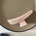 Macro detail of a large matte pink hair claw clip with French lettering on a tray - Pink