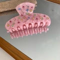 Macro shot of pink marble acetate hair claw with multi-color rhinestones on mirror - Pink