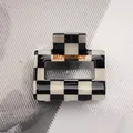 Dettaglio della molletta per capelli a scacchi con finitura lucida e logo - Griglia Bianco e Nero - Quadrato Piccolo