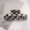 Dettaglio della pinza per capelli a scacchi bianchi e neri con logo dorato del marchio - Griglia Bianco e Nero - Croce