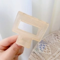 Detail view of a square hollow hair claw clip in translucent peach resin material - 5cm / Jelly Apricot
