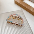 Detail of a marble-pattern acetate hair claw with gold alloy frame on a glass tray - Mermaid Pink