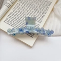 Dettaglio della grande pinza per capelli blu marmorizzata con fiori e strass su un libro - Blu / 11cm