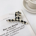 Detail of 11cm checkerboard hair claw clip next to a coffee cup and white magazine - One-word Shape