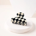 Detail of checkered hair claw clip on a minimalist white stand showing retro fashion design - Fan-shaped