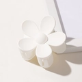 Detail of a white flower hair claw clip with a matte finish and spring closure mechanism - White