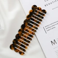 Detailed close-up of amber tortoiseshell resin hair comb with wavy edge design on silk - 14.7*4.7cm / Tortoise