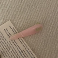 Detail of leaf-shaped light pink resin hair clip with gold metal accent on beige fabric - Pink