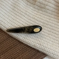 Amber tortoiseshell acetate hair clip with gold logo detail on a cozy knit beanie - Black Texture