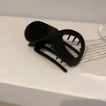 Dettaglio di un fermaglio per capelli nero opaco con design a torsione minimalista - Nero opaco
