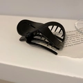 Molla per capelli nera lucida con design a incrocio su sfondo minimalista - Nero Lucido