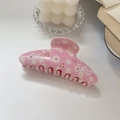 Detailed macro view of pink acetate daisy claw clip with rhinestones on a book - Pink