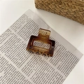 Minimalist rectangular hair claw clip in translucent amber brown on newspaper backdrop - Small / Glossy Caramel