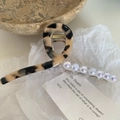 Détail d'une pince à cheveux écaille de tortue avec des perles irisées sur papier - Écaille Claire