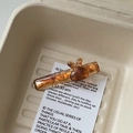 Détail d'une pince à cheveux lapin en acétate marron avec base ambre sur une carte beige - Brun Ambré