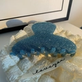 Vue détaillée de la pince à cheveux bleue pailletée en acétate sur un tissu blanc doux - Bleu Pailleté (A3-1-16)