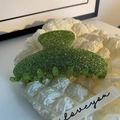 Close-up of green glitter acetate hair claw clip with silver sparkles on white fabric - Glitter Green