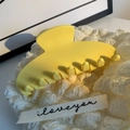 Macro shot of smooth yellow acetate claw clip on white textured fabric background - Yellow