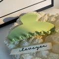 Gros plan d'une grande pince à cheveux en résine vert citron sur un tissu blanc texturé - Vert Fruit