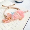 Gros plan d'un chouchou chat rose avec un charme de poisson bleu sur un carnet - Rose Sakura