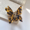 Detail of tortoiseshell butterfly hair claw clip with acetate finish on an open book - Leopard Print (8cmx6.8cm 28g)