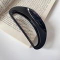 Dettaglio della molletta per capelli nera Creation France con scritta dorata sul libro - Nero