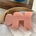 Close-up of pink acetate shark clip with round rhinestone pattern on a stone tray - 9cm / Pink