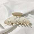 Detail of cream acetate hair claw clip featuring sparkling rhinestone star patterns - Milky White