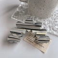 Detail einer wellenförmigen Haarklammer aus Acetat mit grauer Marmorierung auf hellem Tisch - Grau / 8.8cm